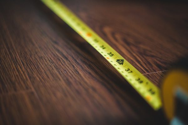Yellow tape measure extended across a dark wooden floor, highlighting measurement details.