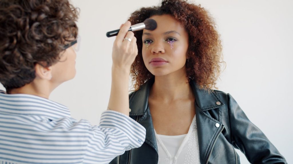Makeup artist applying foundation to a woman's face.