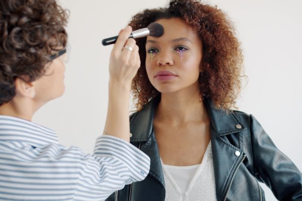 Makeup artist applying foundation to a woman's face.