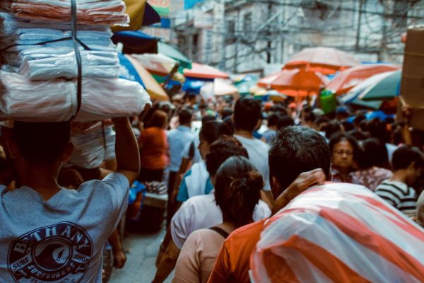 A crowded street market scene in Manila, showcasing vibrant local life under colorful umbrellas.