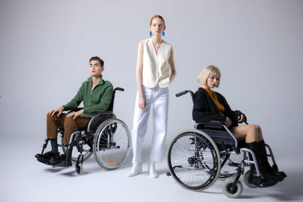 Diverse group showcasing inclusive fashion with wheelchairs in a studio setting.