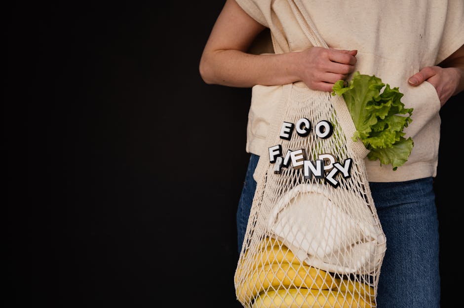 Person holding a string bag with eco-friendly text, lettuce, and bananas against a dark background.