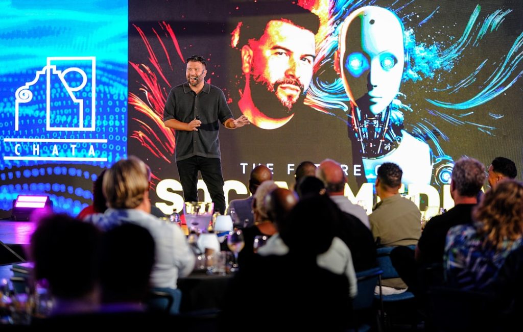 Man presents on stage with robot graphic background