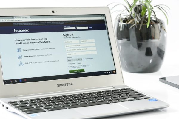 Open Samsung laptop showing Facebook sign-up page next to a potted plant. Ideal for technology themes.