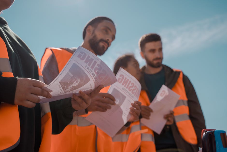Group of volunteers in orange vests distributing missing person flyers outdoors.