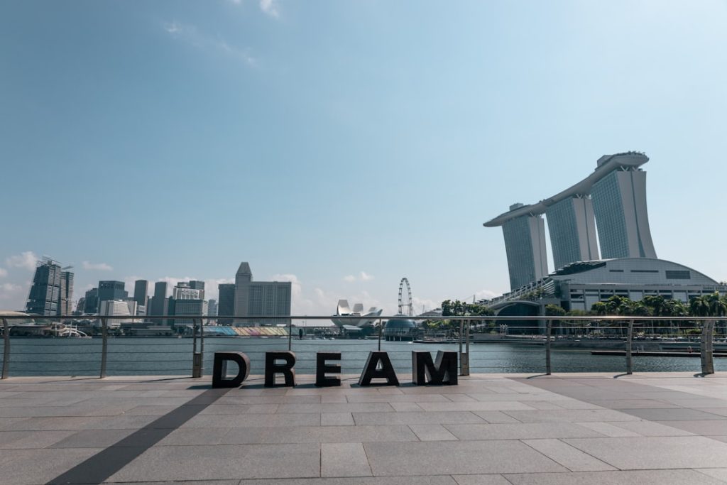 a sign that says dream in front of a body of water