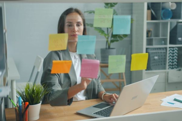 Businesswoman strategizing with sticky notes in a modern office environment.