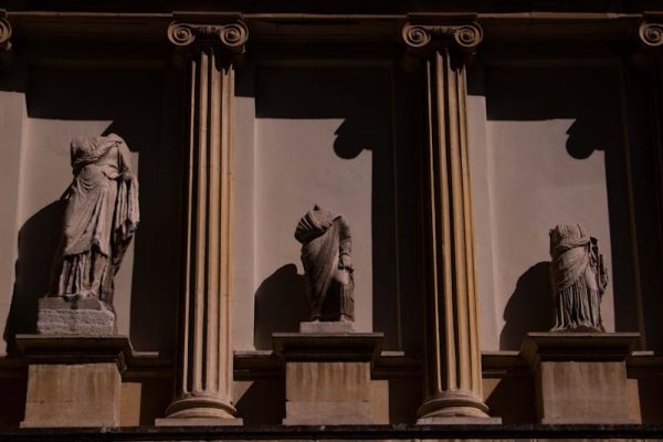 Three headless statues adorn a neoclassical facade in Istanbul, Türkiye, highlighting ancient art.