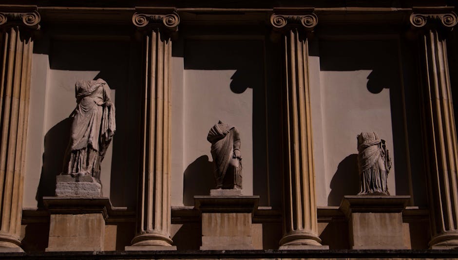 Three headless statues adorn a neoclassical facade in Istanbul, Türkiye, highlighting ancient art.