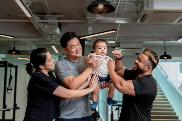 A joyful family moment captured indoors at a gym in Singapore, showcasing happiness and unity.