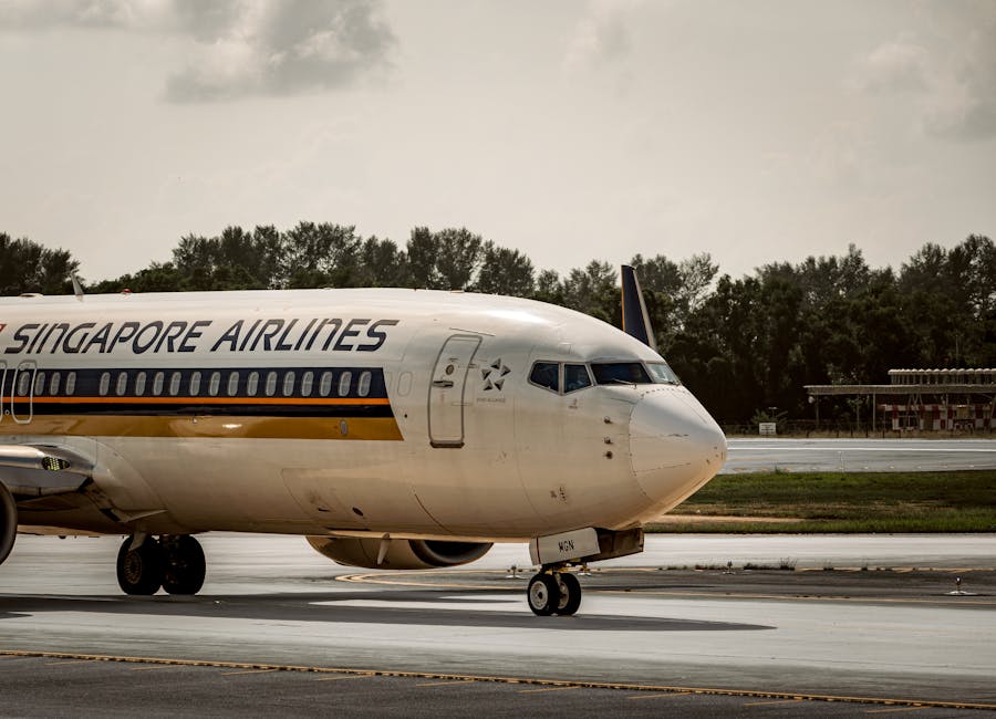 Singapore Airlines plane taxiing on airport runway under cloudy skies.
