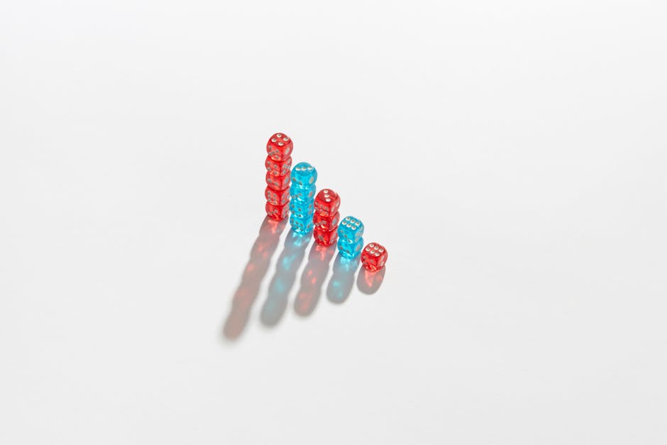 Artistic arrangement of red and blue dice in stacks casting shadows on a white surface.