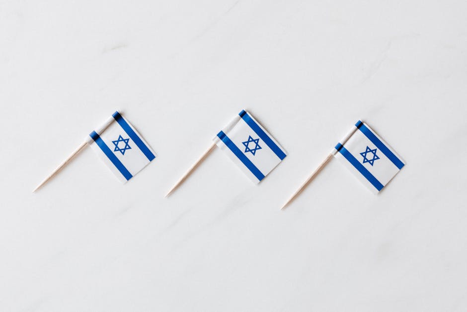 Top view of Israeli flags with blue and white stripes and Davids star in center wrapped on toothpicks placed on white background