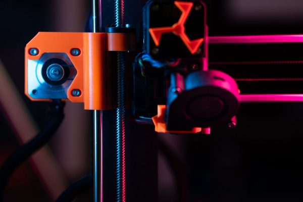 A detailed close-up of a 3D printer showcasing its extruder and components under vibrant lighting.