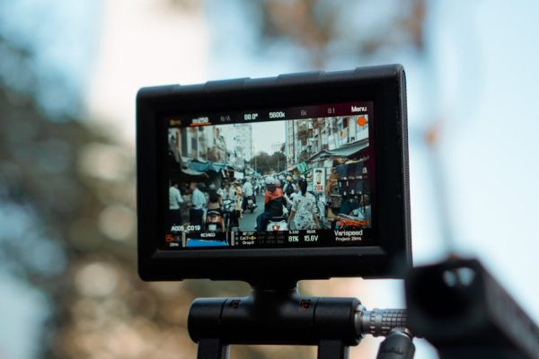 Close-up of a camera monitor showing a bustling street market scene in daylight.