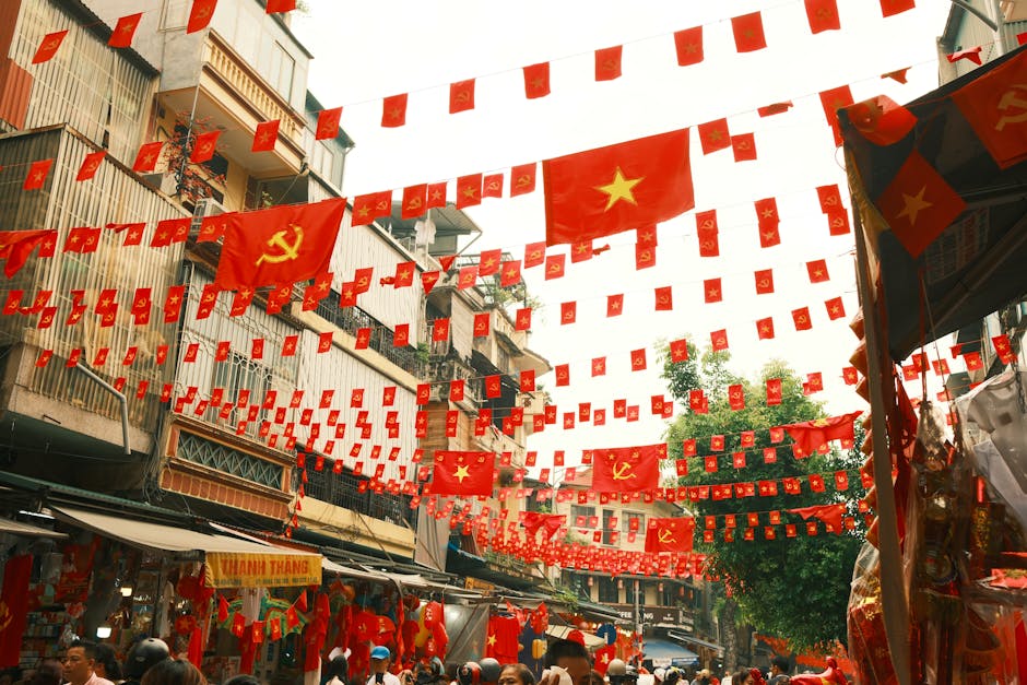 A bustling market street in Vietnam adorned with Vietnamese flags and communist symbols, creating a vibrant atmosphere.