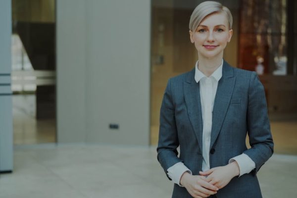 Confident businesswoman in a suit standing indoors in an elegant office setting.