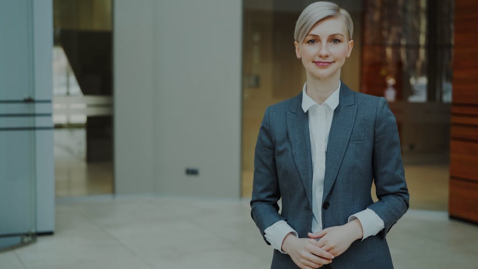 Confident businesswoman in a suit standing indoors in an elegant office setting.