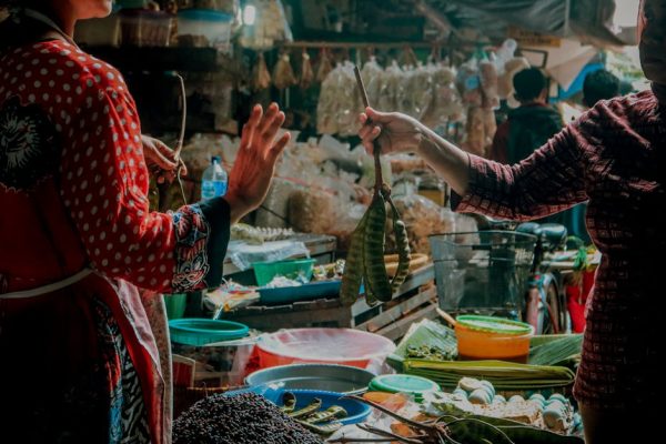 A vibrant street market in Indonesia with two women selling vegetables.