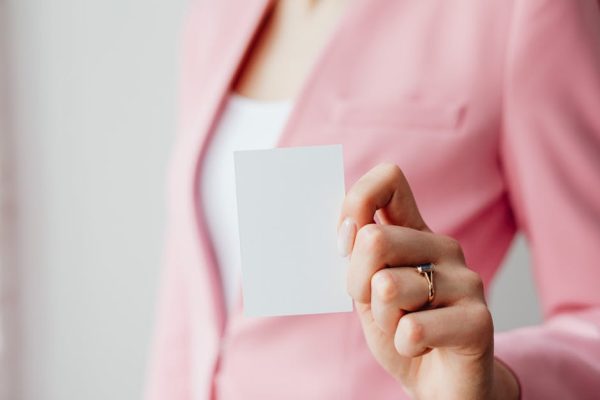 Close-up of a woman's hand holding a blank business card with a blurred background for design mockup.