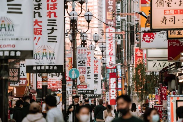 Bustling urban street in Osaka, Japan, filled with colorful signage and diverse crowd.