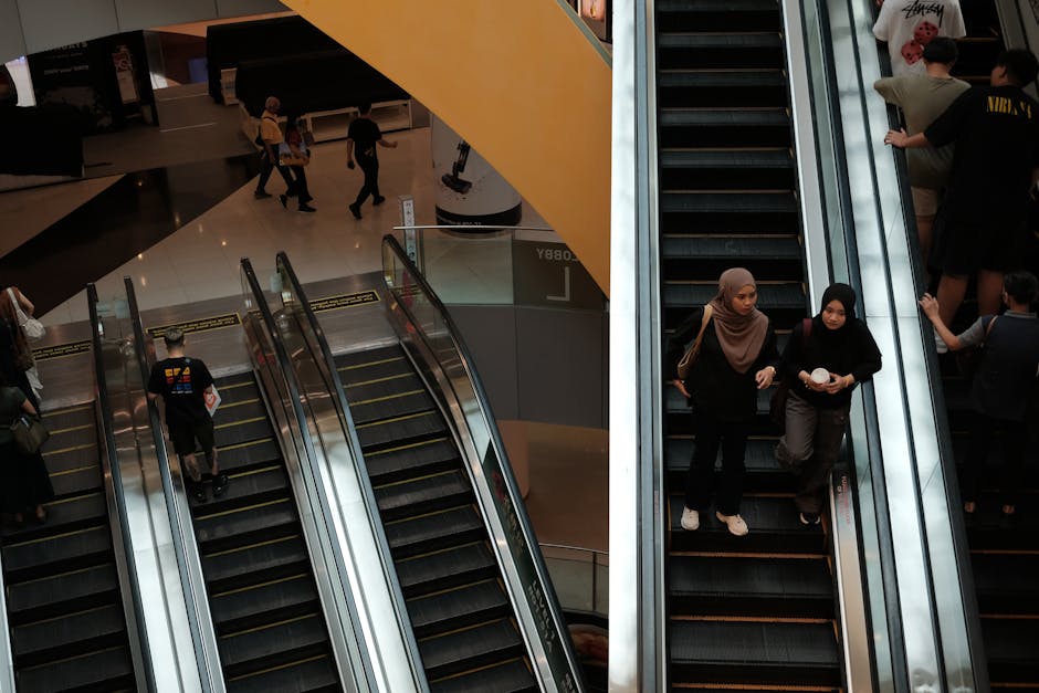 Daily hustle in a Singapore shopping mall, featuring busy escalators and diverse visitors.