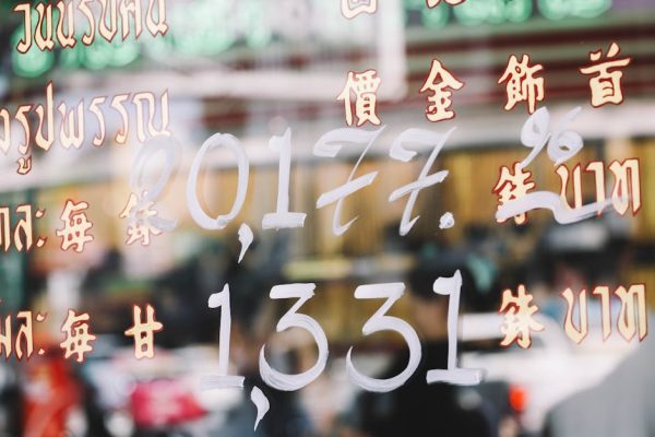 Colorful street reflections with Asian scripts in a bustling Bangkok market.