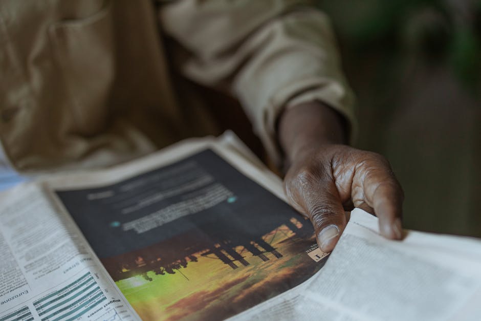 Detailed close-up of a person holding and reading a newspaper indoors.