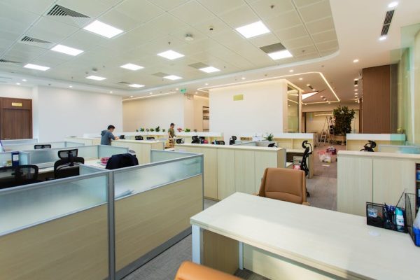 Bright and spacious office interior featuring open-plan cubicles, modern furniture, and ceiling lights.