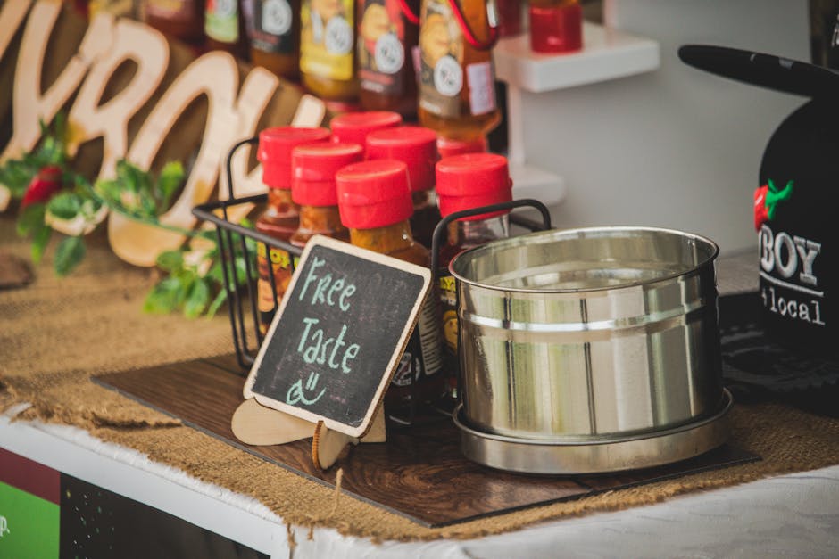 Close-up of spice bottles with free tasting sign on a rustic market counter.