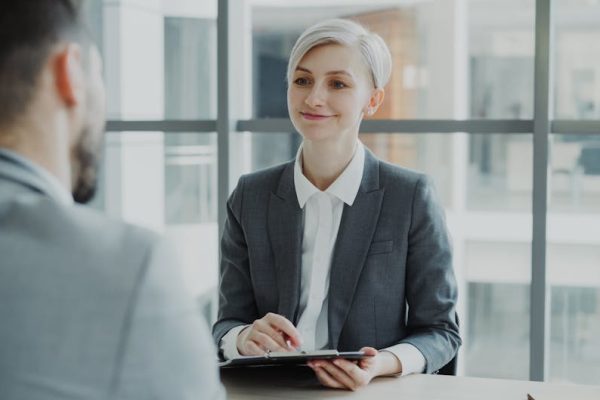 Confident woman interviewing candidate in a modern office. Ideal for business and HR visuals.