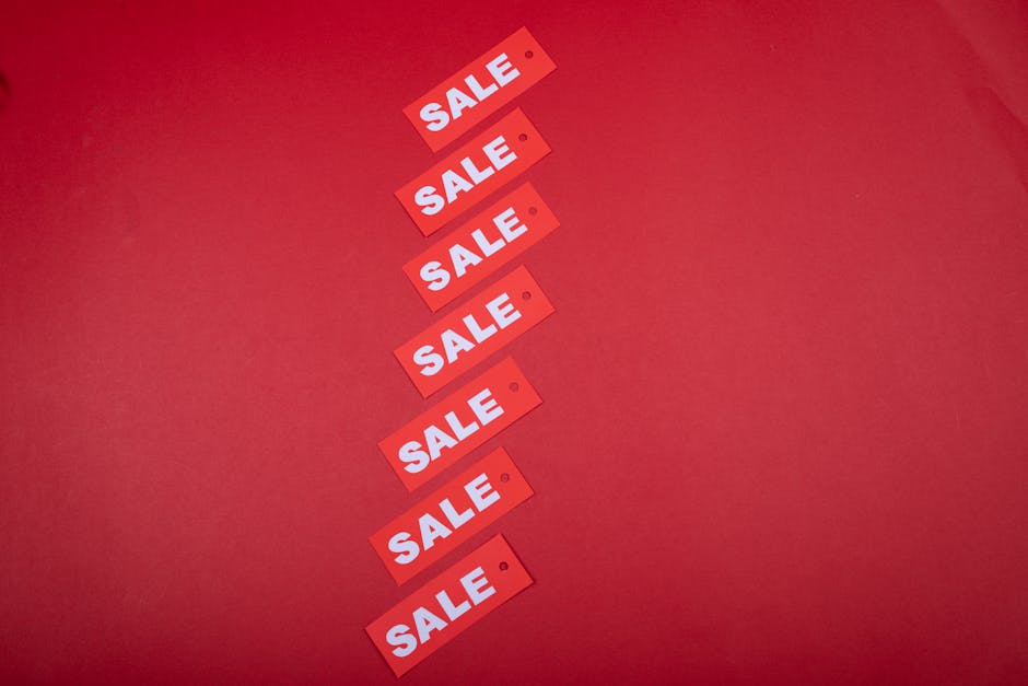 Top view of red sale tags arranged on a vibrant red background for commercial use.