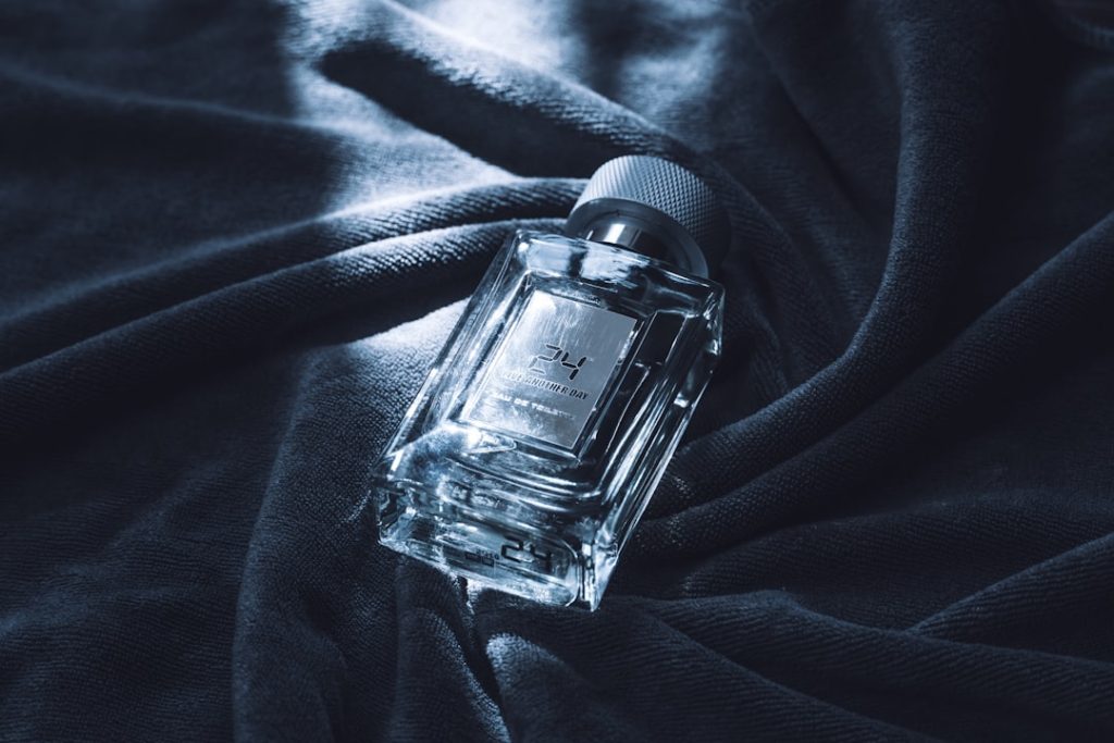 A clear glass bottle of perfume on dark fabric.