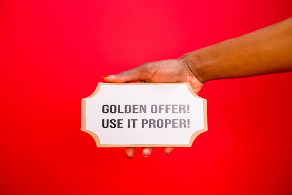 A hand holds a 'Golden Offer' sign on a vibrant red background, symbolizing deals and promotions.