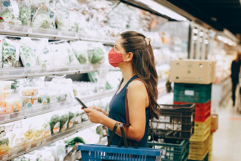 Woman with mask shopping in a grocery aisle, examining fresh produce selection.