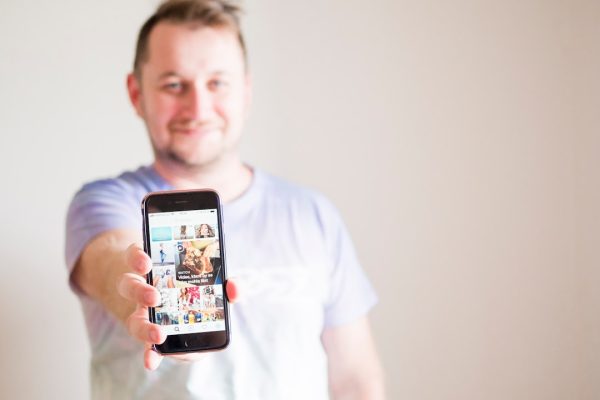 man wearing grey shirt holding smartphone
