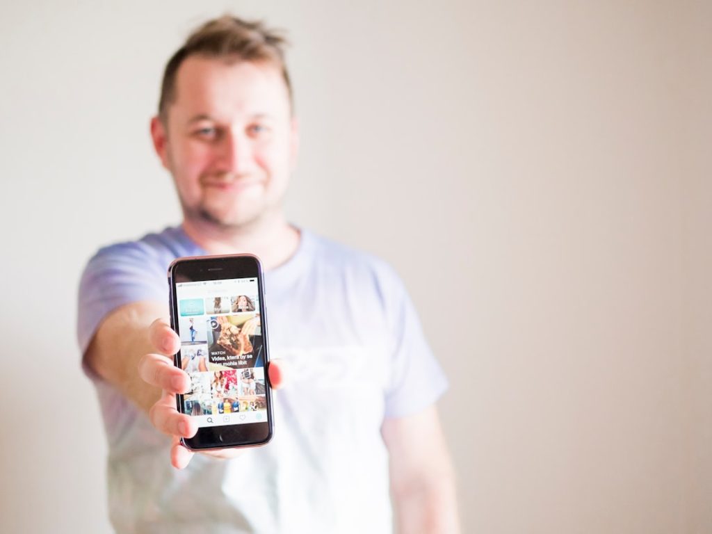 man wearing grey shirt holding smartphone