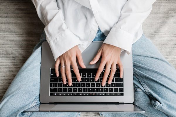 Hands of a person typing on a laptop while sitting on bed. Perfect for tech or lifestyle concepts.