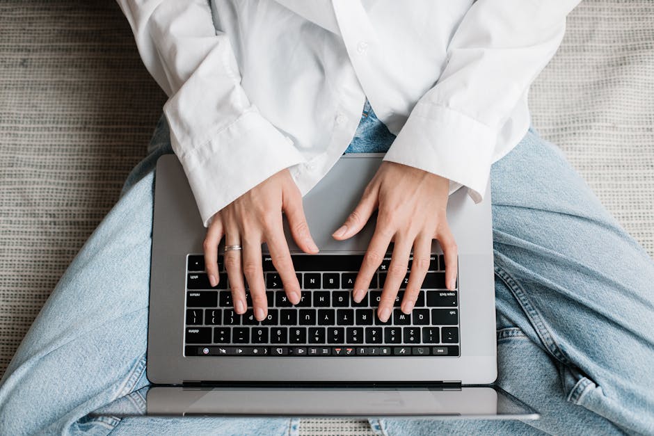 Hands of a person typing on a laptop while sitting on bed. Perfect for tech or lifestyle concepts.