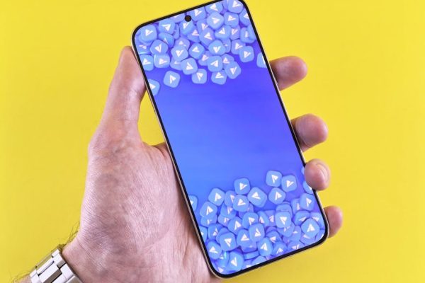 Smartphone displaying social media icons, held in a hand against a bright yellow background.