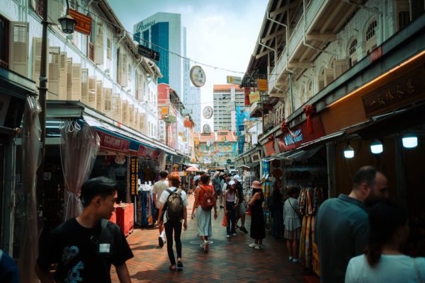 Vibrant street market in Singapore's Chinatown with tourists exploring shops and stalls under historic architecture.