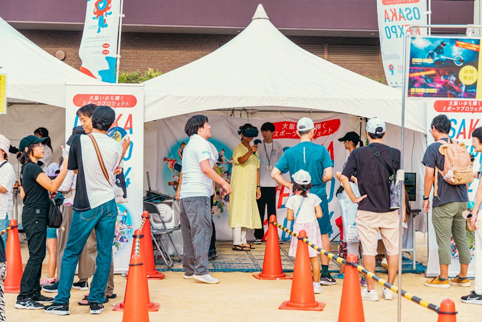 People gather at an outdoor fair booth, enjoying a virtual reality experience in a festive setting.