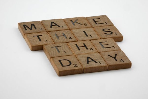 Wooden Scrabble tile pieces arranged to spell 'Make this the day'.